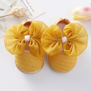 Sweet yellow baby girl princess shoes featuring a large mesh bow and soft flexible sole