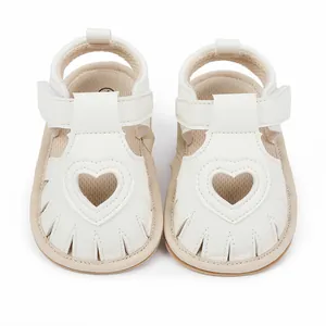 Close-up view of these white baby sandals featuring a decorative heart-shaped cutout.