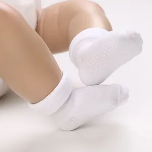 Macro close-up of white breathable mesh baby socks with turnover cuffs on a doll