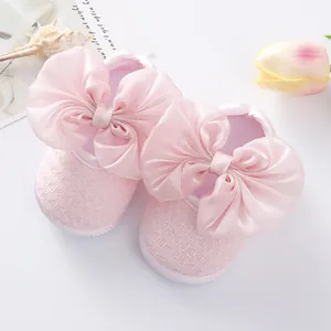 Detailed view of pink newborn baby princess shoes with large decorative satin bows