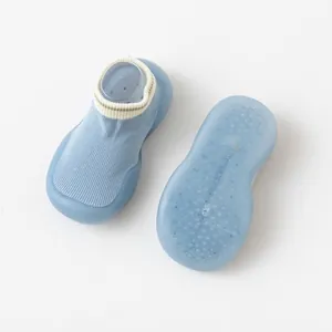 Détail de la semelle antidérapante en silicone bleu souple des chaussons de bébé.