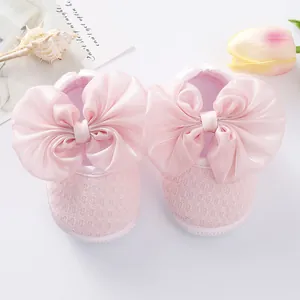 Close-up detail of pink baby princess shoes with large satin bows and soft mesh