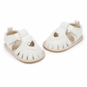 Close-up of white baby sandals featuring a decorative heart-shaped cutout on the front.