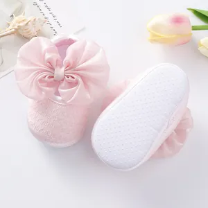 Close-up of pink baby princess shoes featuring large satin bows and anti-slip soft soles.