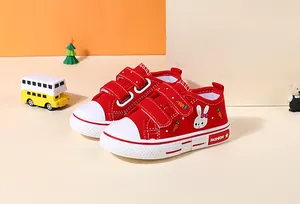 Detail of red children's canvas shoes with rabbit and carrot prints and velcro straps