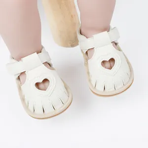 Detailed view of white baby sandals featuring a heart-shaped cutout and Velcro strap
