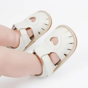 Close-up detail of white baby sandals with heart cutout and soft leather texture