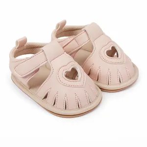 Close-up detail of the heart-shaped cutout and stitching on pink faux leather baby sandals