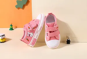 Pink children's canvas shoes with cute bunny and carrot patterns and velcro straps.