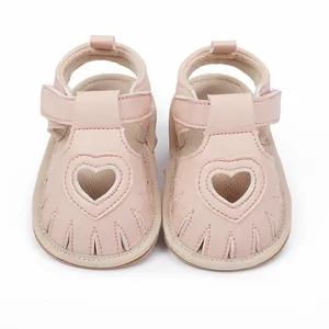 Front view of pink baby sandals with decorative heart cutouts and velcro straps.