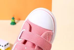 Close-up of pink toddler canvas shoes featuring white rubber toe and velcro straps