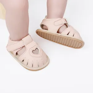 Detail of soft pink baby sandals featuring a sweet heart-shaped cutout design.
