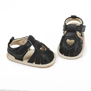 Close-up of black baby sandals featuring a heart-shaped cutout design and Velcro strap.