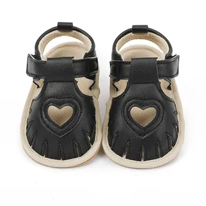 Close-up of black baby sandals with heart-shaped cutouts on a white background