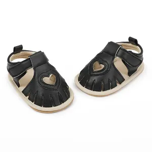 Close-up of black baby sandals with heart-shaped cutouts and soft Velcro straps.