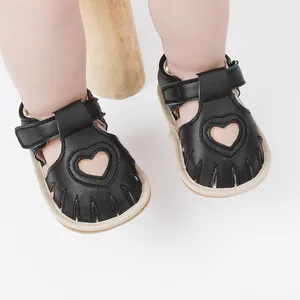 Close-up of black baby sandals with heart cutout design and soft soles for toddlers