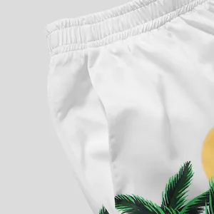 Close-up of white Hawaiian beach shorts featuring tropical palm tree print and elastic waist.