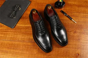 Zapatos Oxford clásicos de cuero negro en un escritorio con accesorios de oficina detalle