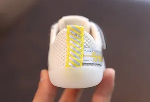 Détail de l'arrière d'une chaussure de marche pour bébé en maille respirante blanche.