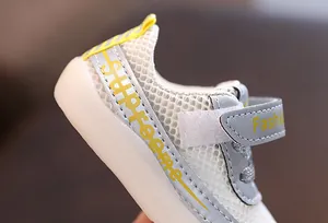 Gros plan de chaussures de marche respirantes en mesh blanc pour bébé avec velcro