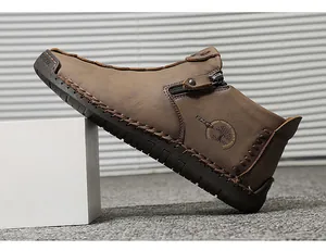 Close-up of brown leather high-top shoe with side zipper and hand-stitched details.