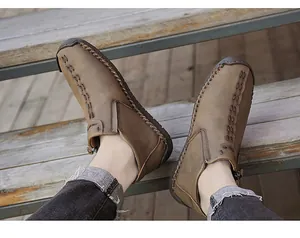 Detailed view of brown men's high-top leather shoes with handmade stitching and side zipper.