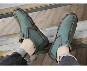 Detailed view of teal green high-top men's shoes with contrast hand-stitching on leather.
