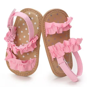 Detailweergave van roze babysandalen met elegante ruches en charmante stippenzolen