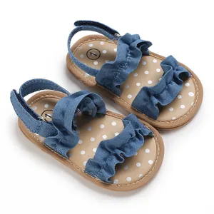 Gedetailleerd beeld van denim blauwe babysandalen met ruches en een witte stippenprint