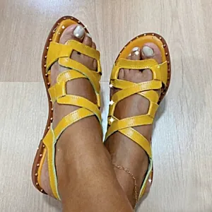 Detailed close-up view of yellow criss-cross strap flat sandals for women on feet