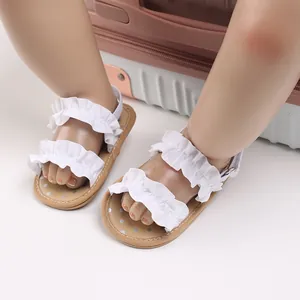 Detailopname van witte baby sandalen met ruches op poppenvoetjes met antislipzool