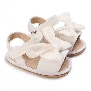 Close-up of white baby girl sandals with large bow and soft corduroy fabric