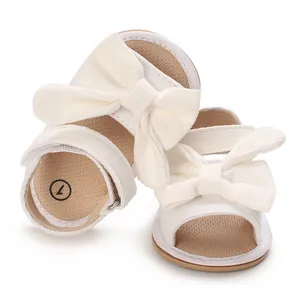 Close-up detail of soft-soled baby girl summer sandals with large decorative cream bows