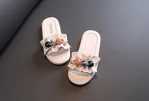 Detailed top view of girls' white summer slides featuring colorful beads and ruffle design