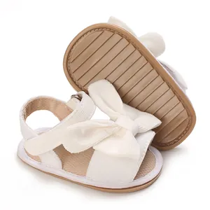 Detail view of baby girl sandals featuring a large bow and anti-slip rubber soles