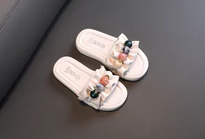 Close-up of girls' beige ruffled fashion slippers with colorful decorative pearl beads