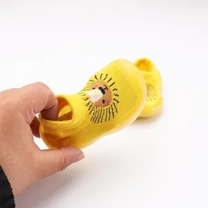 Detailopname van gele baby sokschoenen met leeuw cartoon en elastische enkelmanchet