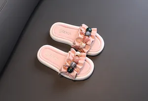 Detailed view of girls' pink slides featuring ruffled straps and decorative colorful beads
