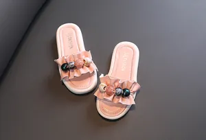 Close-up detail view of pink girls' ruffled slippers with colorful decorative beads.