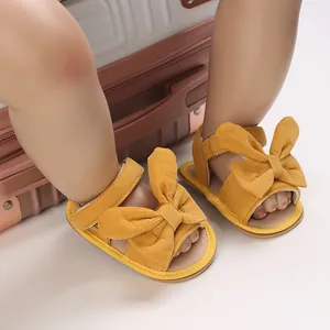 Close-up of yellow corduroy baby girl sandals with large bowknots for summer wear