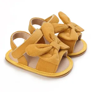 Detailed view of mustard yellow baby girl sandals featuring a soft corduroy bow