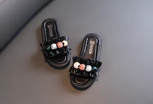 Close-up detail of girls' black ruffled slippers with colorful decorative beads