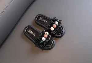 Close-up of black children's slides with ruffle strap and colorful bead accents