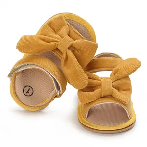 Detail view of yellow baby girl sandals with decorative bows and corduroy texture