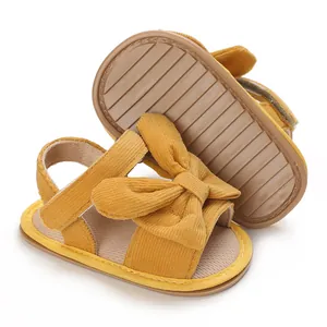 Macro detail of baby girl yellow corduroy bow sandals showing flexible anti-slip rubber sole