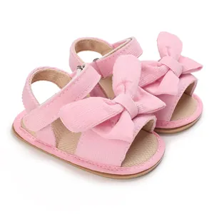 Close-up of pink baby girl sandals with large corduroy bow detail