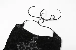 Detail eines schwarzen, transparenten Kleids mit Blumenmuster und Neckholder.