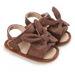 Close-up detail of brown corduroy baby girl sandals featuring large decorative bows