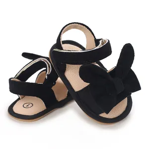 Detailed close-up of black corduroy baby girl sandals featuring a decorative bow.