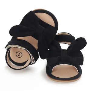 Detailed macro shot of black corduroy baby girl sandals featuring a large decorative bow